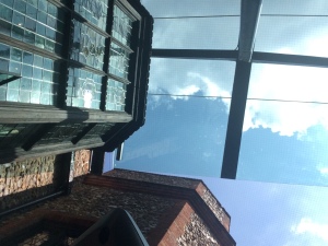 A photo looking up towards the sky in the café. You can see a glass roof covering part of the area. 