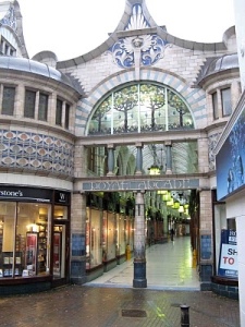 Large archway leading inside Royal Arcade. Stone column and decorative tile work in blues and greys. 